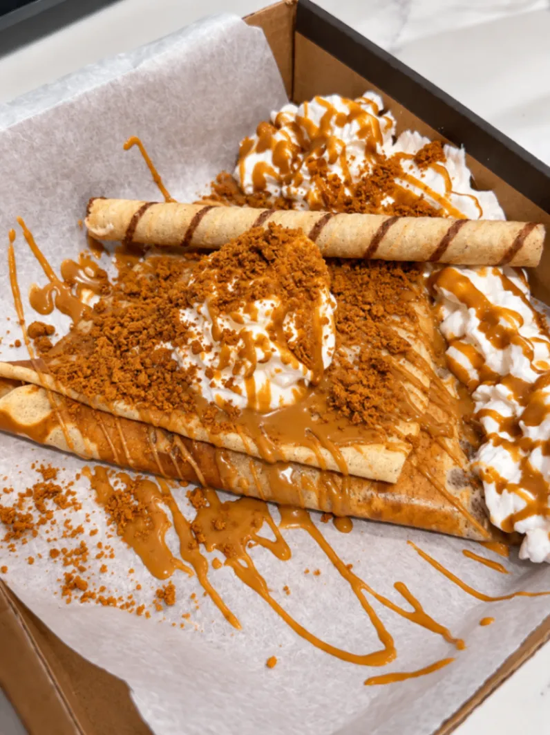 Biscoff crepe in a kraft box covered with Biscoff crumble, Lotus Biscoff drizzle, whipped cream and a rolled wafer