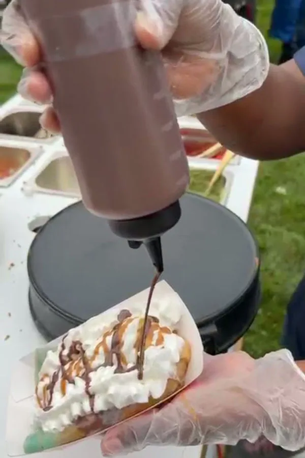 Chocolate sauce being drizzled over a fresh crepe at the live station